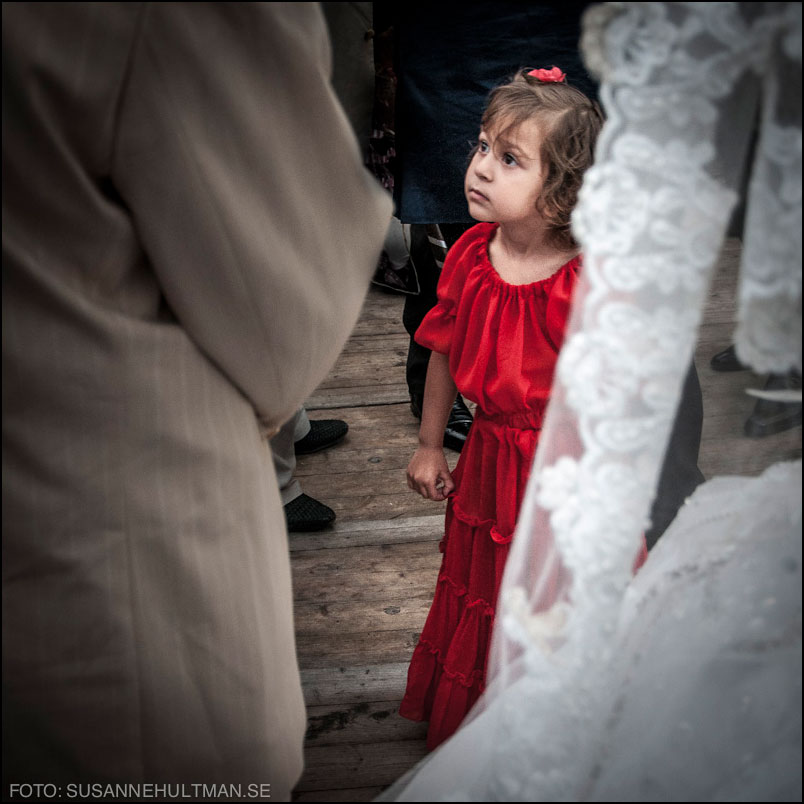 Flicka i röd klänning bakom bruden