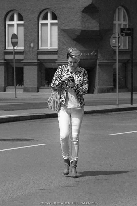 Kvinna korsar gatan fullt upptagen med sin mobil