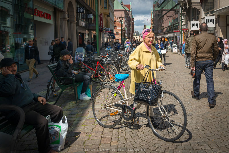 Kvinna med cykel på gågatan
