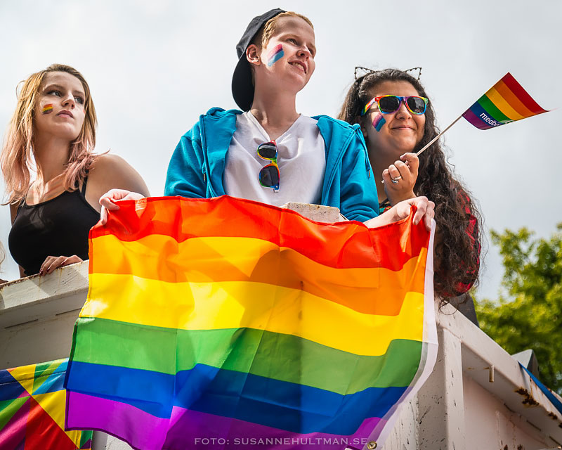 Tre tjejer med regnbågsflaggan