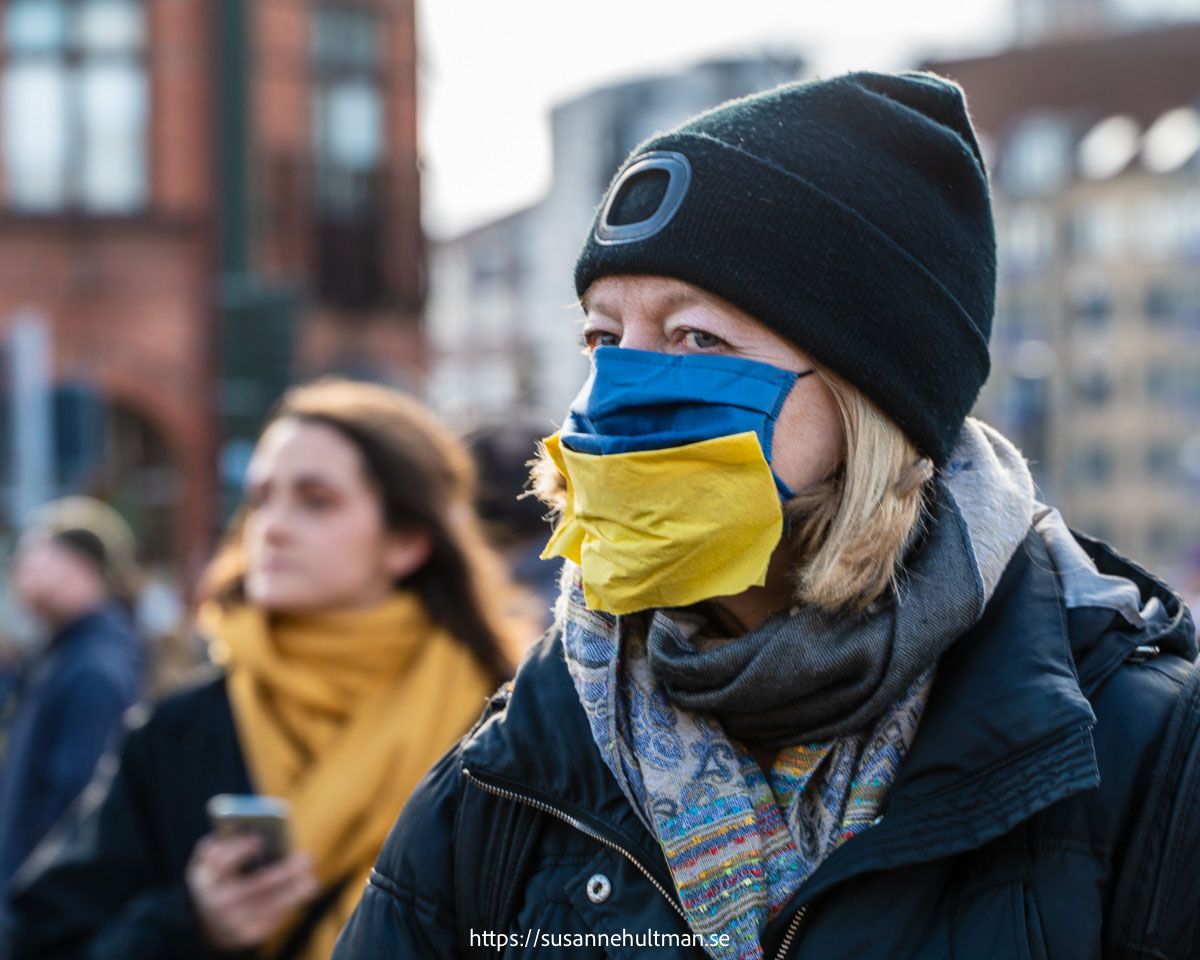 Kvinna med munskydd i gult och blått.