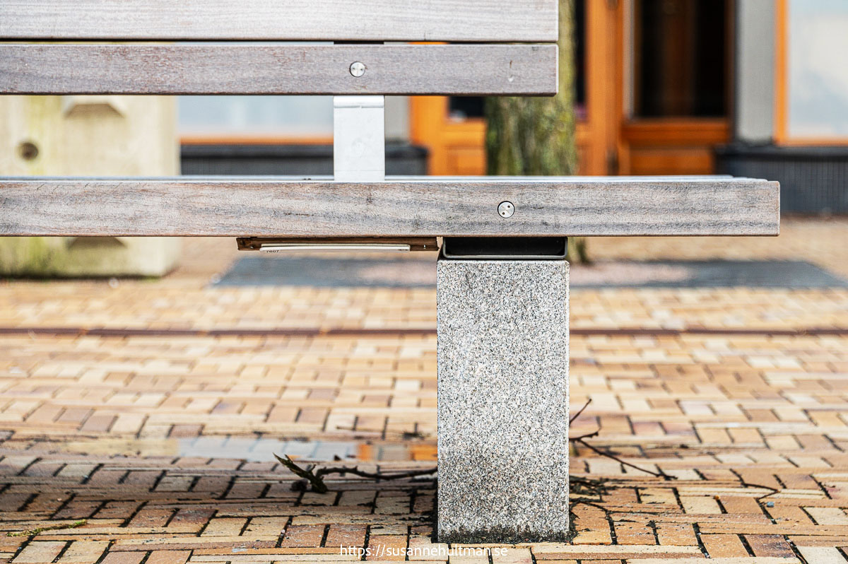 Träbänk på betong med vit sensor under bänkens sittyta.