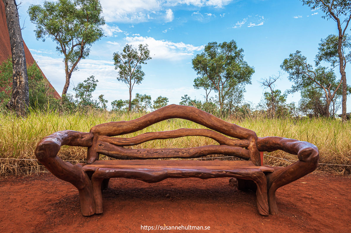 Bänk gjord av grenar. Till vänster syns lite av Uluru.