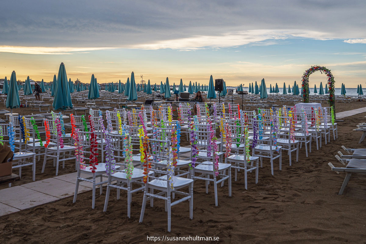 Uppradade stolar med girlanger på stranden.