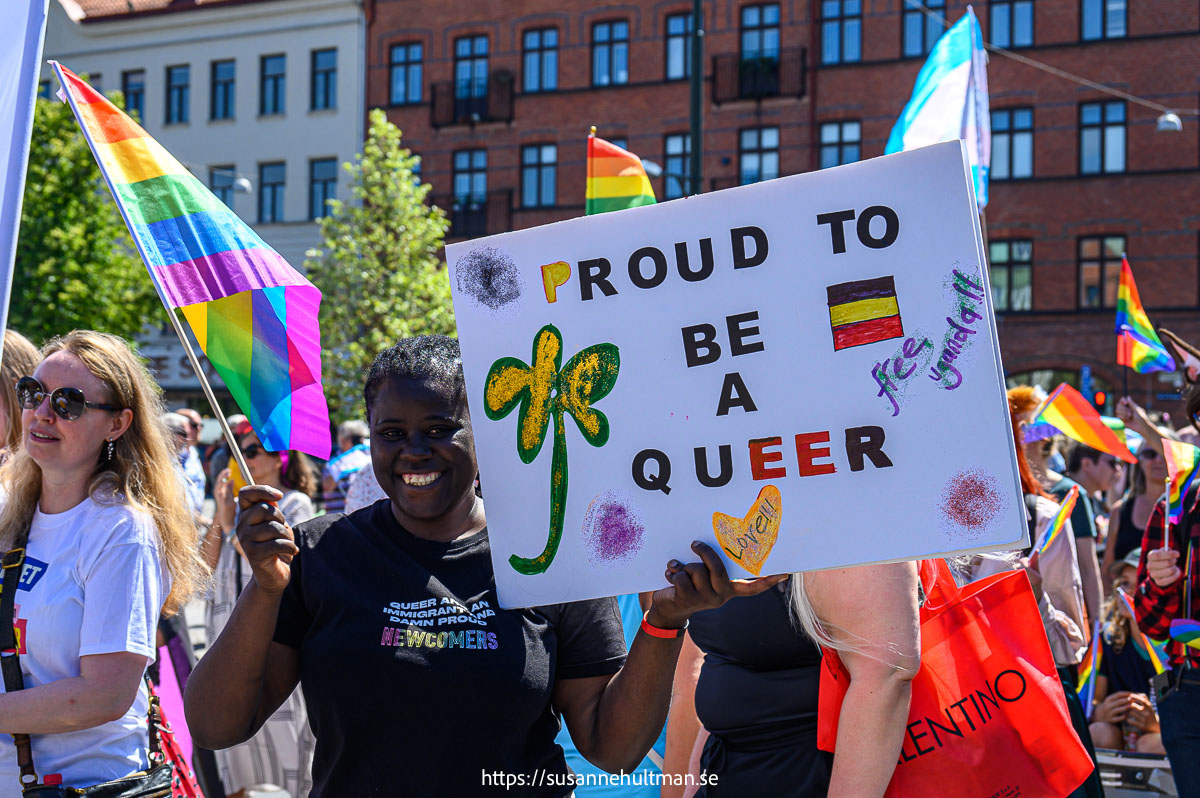 Svart kvinna med plakat med texten "Proud to be a queer" och "Free Uganda".