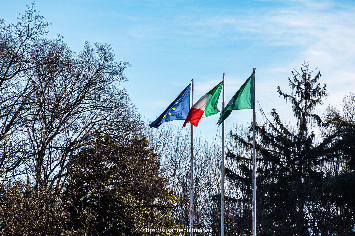 Tre flaggor: EU-flaggan, italienska flaggan och Lombardiets flagga.