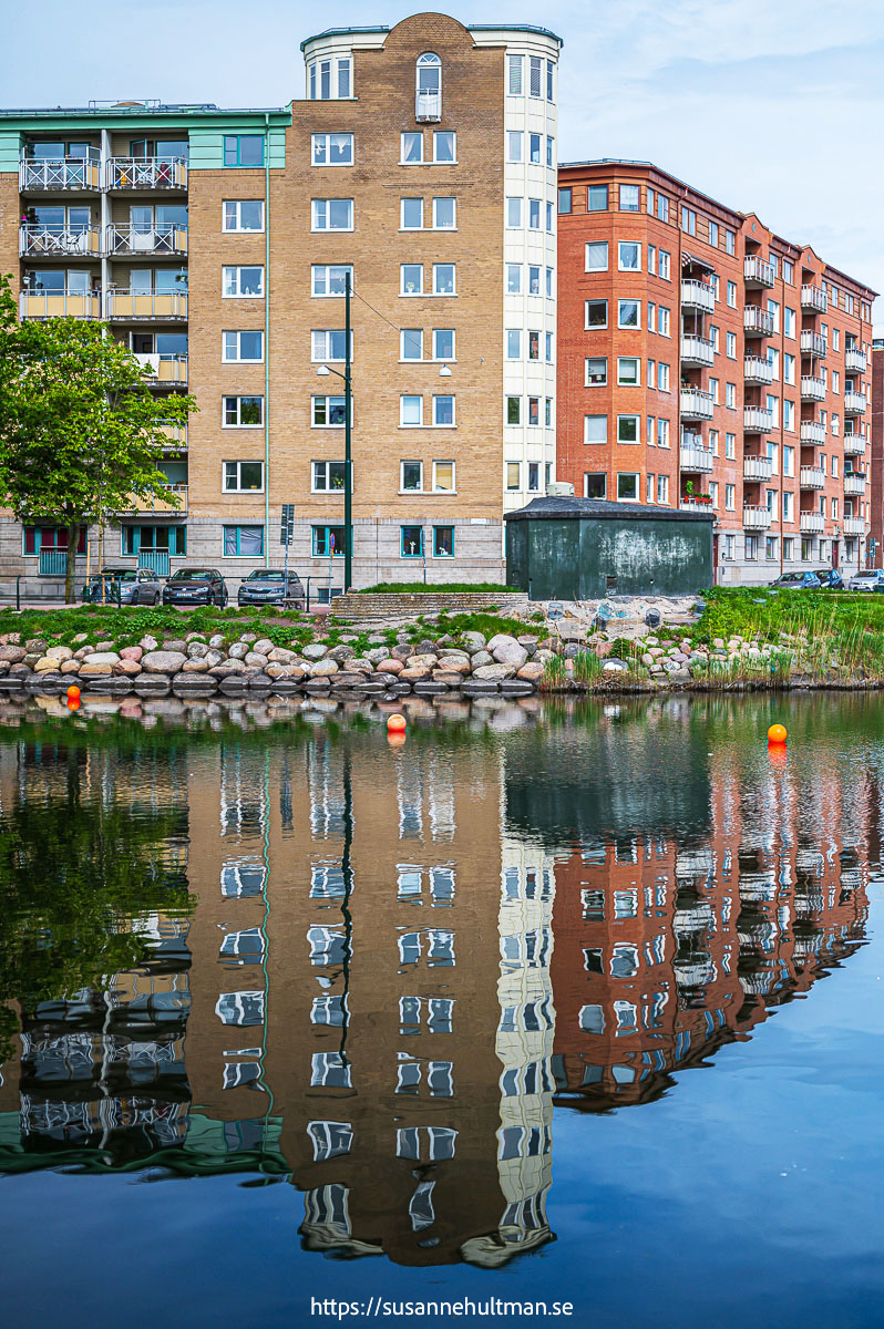 Höga byggnaders om speglas i Malmös kanal.