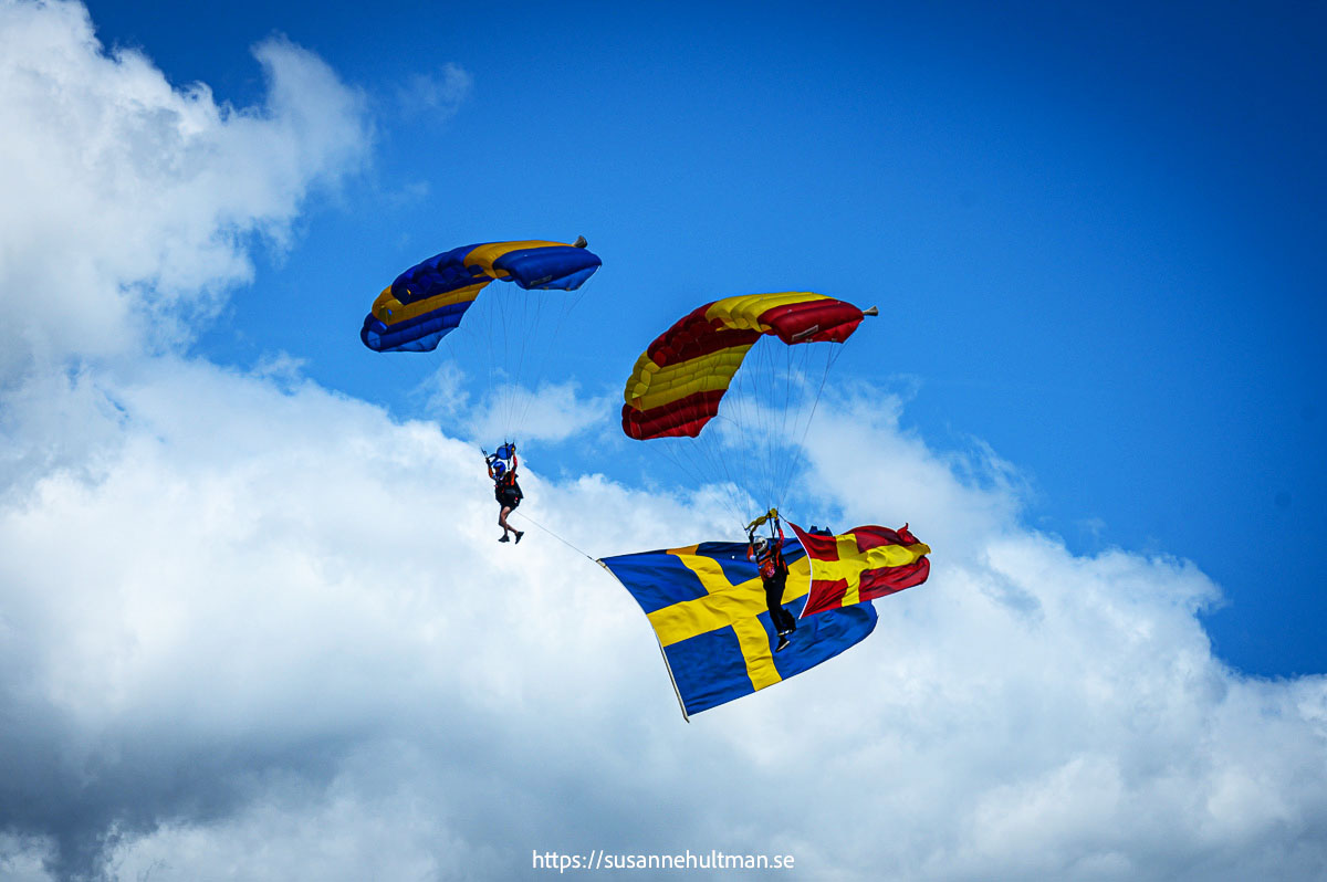 Fallskärmshoppare med svenska och skånska flaggorna.