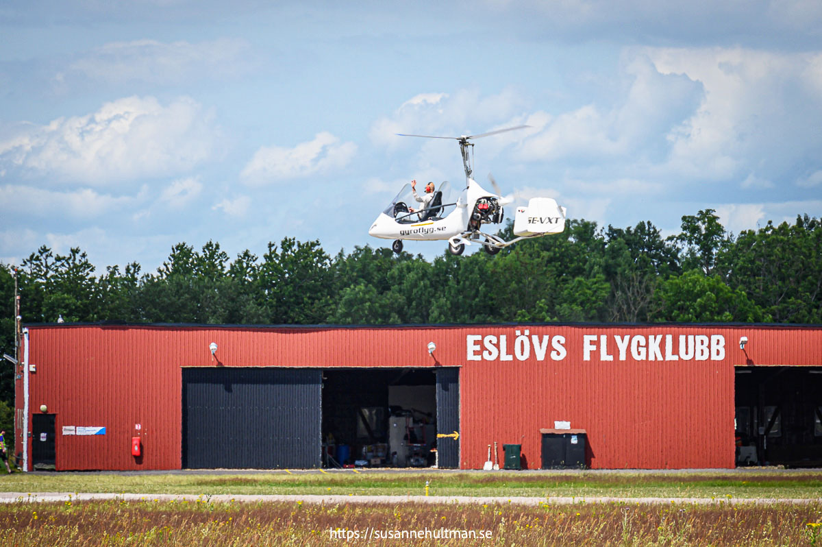 Gyrokopter ovanför hangar med texten ESLÖVS FLYGKLUBB.